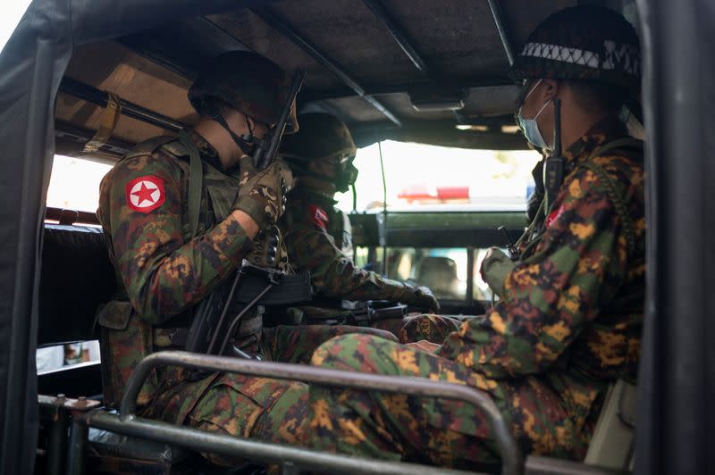 Myanmar soldiers sit inside a vehicle as they guard in front of a Hindu temple in the downtown area in Yangon