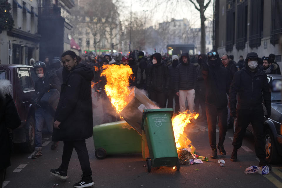 Youths burn garbage containers during a demonstration against plans to push back France's retirement age, Tuesday, Feb. 7, 2023 in Paris. The demonstration comes a day after French lawmakers began debating a pension bill that would raise the minimum retirement from 62 to 64. The bill is the flagship legislation of President Emmanuel Macron's second term. (AP Photo/Thibault Camus)