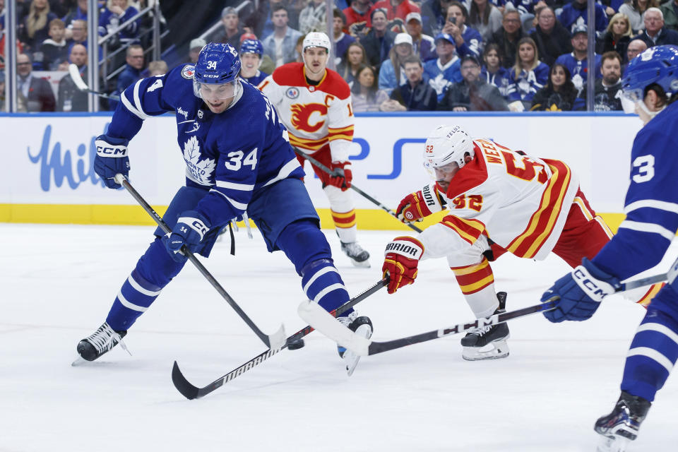 Toronto Maple Leafs centre Auston Matthews (34) tries to a get a shot past Calgary Flames defenseman MacKenzie Weegar (52) during the second period of an NHL hockey game Friday, Nov. 10, 2023, in Toronto. (Cole Burston/The Canadian Press via AP)