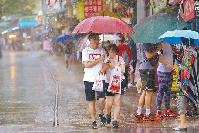 全台防疫措施7日起擴大解禁，各行各業磨刀霍霍，準備搶食振興經濟大餅，原本期待滿滿觀光人潮的淡水老街，受鋒面影響大雨不斷，民眾撐傘逛街。（黃世麒攝）