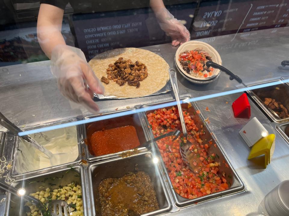 chipotle worker filling orders on the line at a toronto location