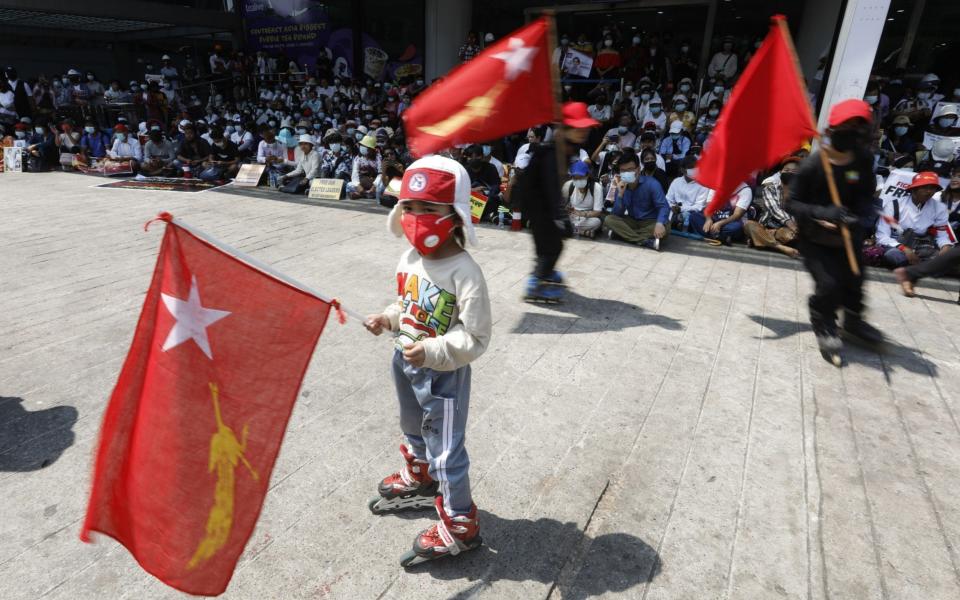 Children hold National League for Democracy (NLD) flags during a protest against the military coup - Shutterstock