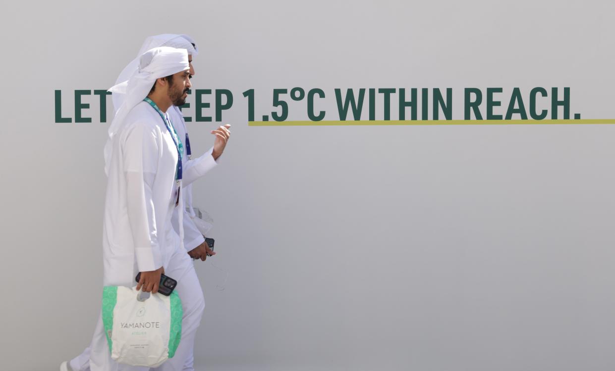 People walk past the slogan: "Let's Keep 1.5 Degrees Celsius Within Reach" prior to the opening ceremony of the UNFCCC COP28 Climate Conference at Expo City Dubai on November 30, 2023 in Dubai, United Arab Emirates.