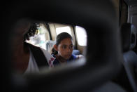 In this Sept. 2, 2018 photo, 10-year-old Venezuelan Angelis sits in a car with her mother Sandra Cadiz as they get a free ride from a driver to the next city, Lebrija, Colombia, on their journey to Peru. A police officer offered to hail down a ride, and a man in an old boxy Chevrolet Samurai agreed to take them. (AP Photo/Ariana Cubillos)