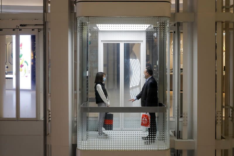People observe social distancing as they share a lift in a department store in Beijing