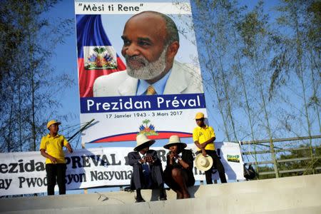 FILE PHOTO: Haitians chat as they wait for the start of the funeral for Haiti's former President Rene Preval in Port-au-Prince, Haiti, March 11, 2017. The poster reads in creole, "Thank you Little Rene. President Preval". REUTERS/Andres Martinez Casares