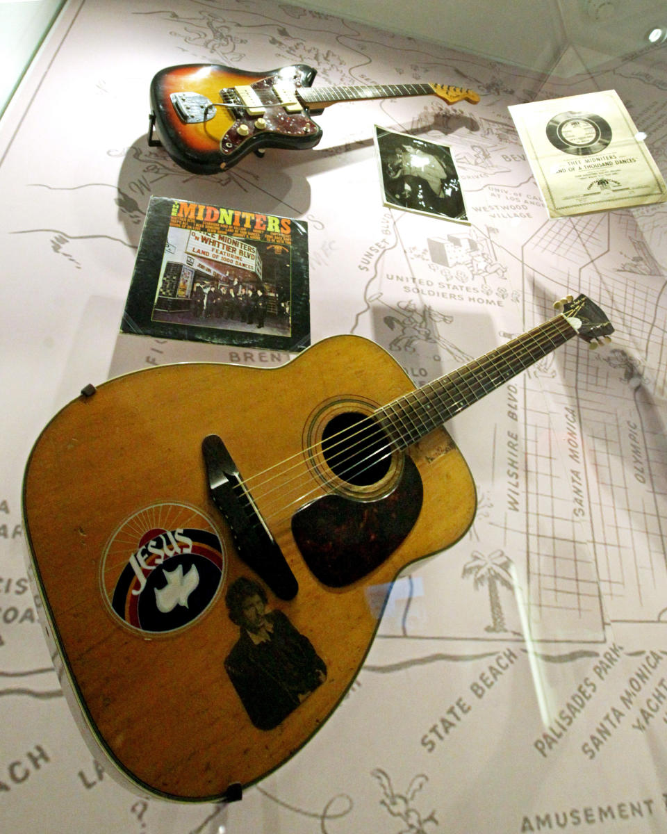 This March 26, 2012 photo shows a Harmony Sovereign acoustic guitar with a Jesus sticker among other items from Chicano musician Little Willie G, aka Willie Garcia, founding member of Thee Midniters in the 1960s, at the exhibit, "Trouble In Paradise: Music and Los Angeles, 1945-1975," at the Grammy Museum in Los Angeles. The museum website says the exhibit focuses on the "tensions between alluring myths of Southern California paradise and the realities of social struggle that characterized the years following WWII." (AP Photo/Reed Saxon)