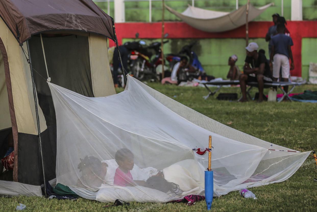 A family wakes inside a mosquito net outside a tent after spending the night at a soccer field following Saturday´s 7.2 magnitude earthquake in Les Cayes, Haiti, Sunday, Aug. 15, 2021. 