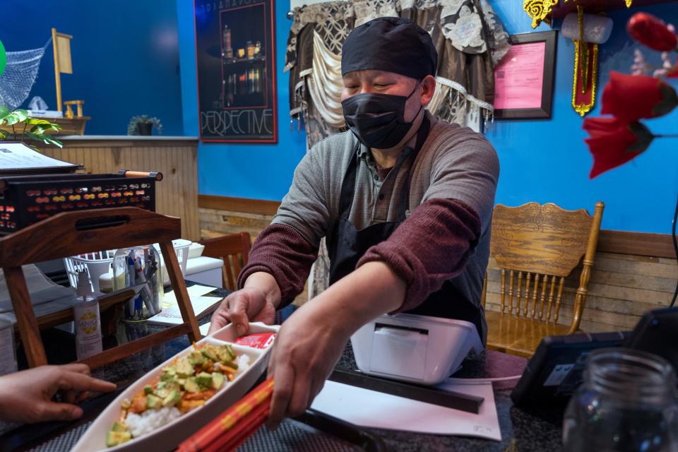 Htira Rammahtaw hands a sushi dish over to be delivered to a customer at Htaw Metta, Wednesday, March 1, 2023 in the Nora area. The northside restaurant, across from North Central High School, offers Burmese food, as well as sushi and Thai cuisine.