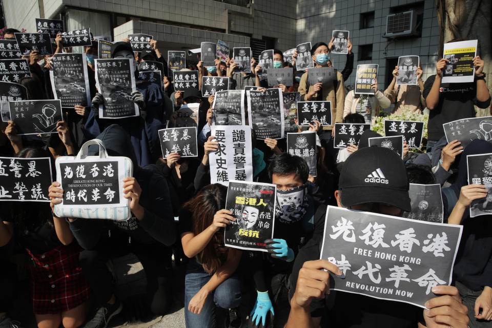 Protesters hold up signs calling for revolution and investigation into police brutality at the University of Science and Technology in Hong Kong on Friday, Nov. 8, 2019. The student from the University who fell off a parking garage after police fired tear gas during clashes with anti-government protesters died Friday, in a rare fatality after five months of unrest that intensified anger in the semi-autonomous Chinese territory. (AP Photo/Kin Cheung)