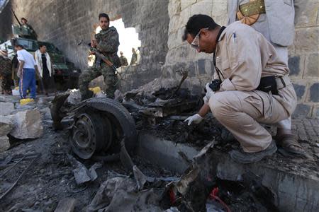 Investigators from the criminal investigation department (CID) examine the wreckage of a car after a bomb exploded outside the main wall outside the central prison in Sanaa February 14, 2014. REUTERS/Mohamed al-Sayaghi
