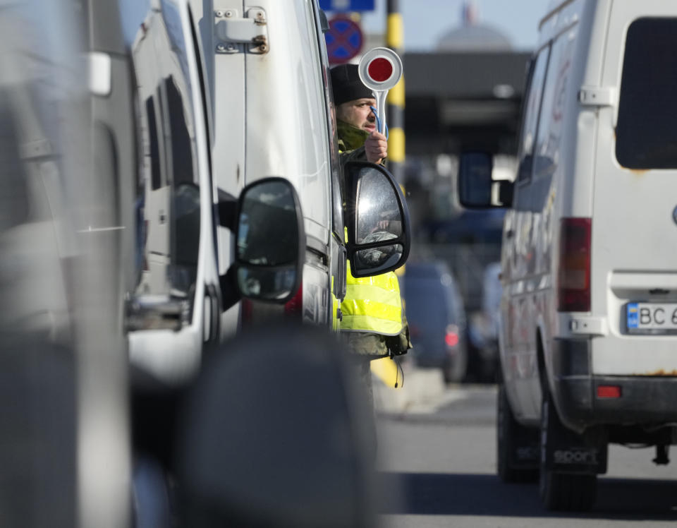 A Polish border guard gives instructions as drivers wait to cross the border from Poland into Ukraine in Medyka, Poland, on Saturday, Feb. 19, 2022. Tensions are soaring in Ukraine's east and Western leaders issue dire warnings that a wider war could be coming. But along Ukraine's border with European Union nation Poland, calm prevails. (AP Photo/Czarek Sokolowski)