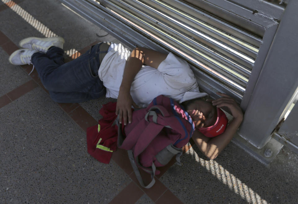 A migrant sleeps on the ground after camping out on the Gateway International Bridge that connects downtown Matamoros, Mexico with Brownsville, Thursday, Oct. 10, 2019. Migrants wanting to request asylum camped out on the international bridge leading from Mexico into Brownsville, Texas, causing a closure of the span. (AP Photo/Fernando Llano)