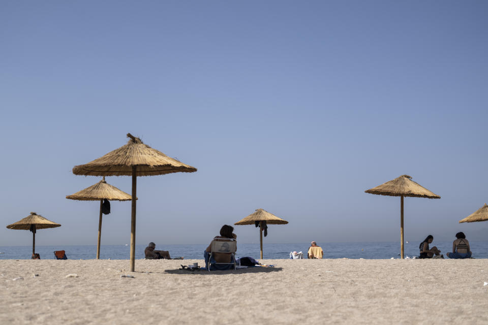 Bathers sit in the shade of umbrellas during a hot day at Glyfada beach near Athens, Friday, July 14, 2023. Temperatures were starting to creep up in Greece, where a heatwave was forecast to reach up to 44 degrees Celsius in some parts of the country over the weekend. (AP Photo/Petros Giannakouris)