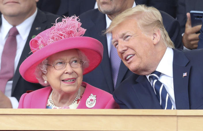 پرزیدنت دونالد ترامپ خم می شود تا چیزی به ملکه الیزابت دوم بگوید، با لباس صورتی با کلاه با پر صورتی.