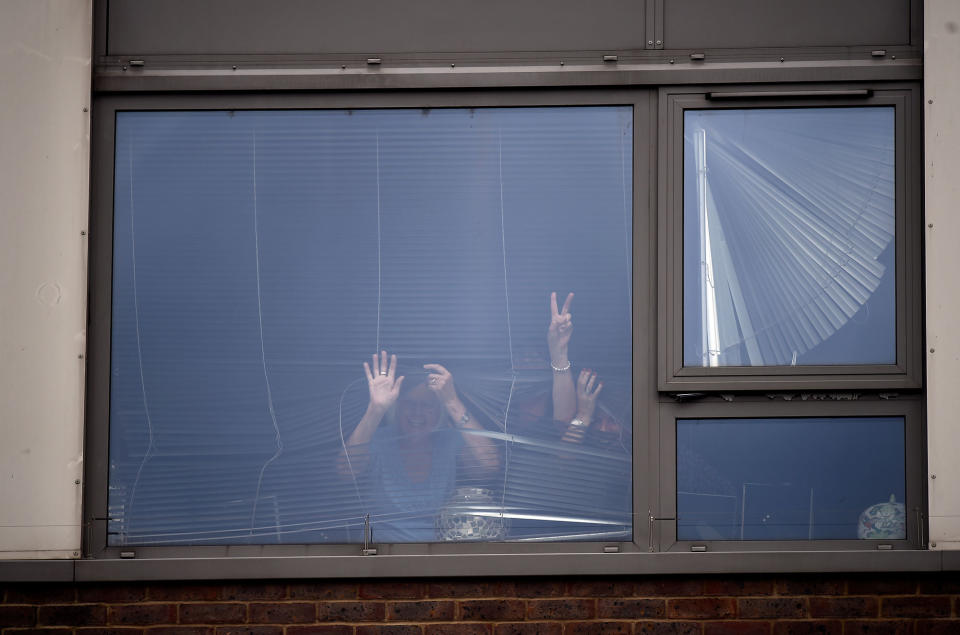 A woman flashes a ‘victory’ sign at a window in the Burnham Tower