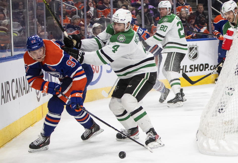 Dallas Stars' Miro Heiskanen (4) and Edmonton Oilers' Connor McDavid (97) battle for the puck during second-period NHL hockey game action in Edmonton, Alberta, Saturday, Nov. 5, 2022. (Jason Franson/The Canadian Press via AP)