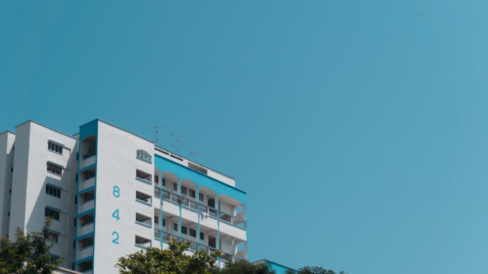 Blue and white HDB Block next to the blue sky