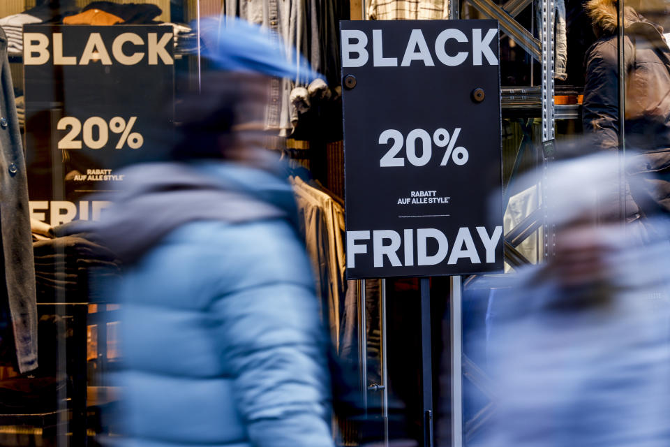 people walking past a shop with black friday signs in the window