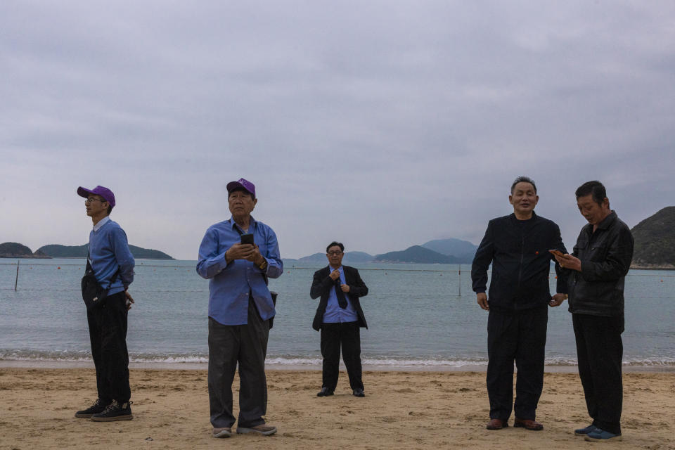 FILE - Mainland Chinese tourists on a budget tour take photographs on a beach in Hong Kong, April 10, 2023. Living in Hong Kong today means juggling contradictory feelings. In 20 interviews, many said that when they focus on business indicators and everyday life, they see a recovery gathering pace after years of travel restrictions. But when it comes to anything political, the openness and freedoms that were once hallmarks of the Chinese-ruled former British colony seem permanently gone. (AP Photo/Louise Delmotte, File)