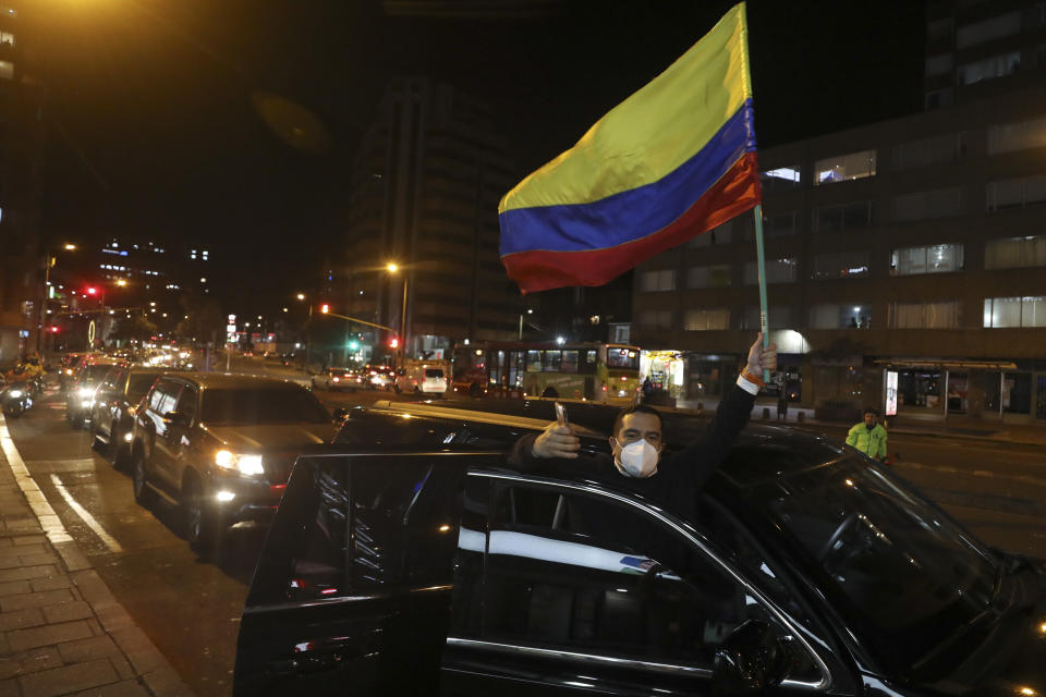 A supporter of former President Alvaro Uribe holding a national flag takes part in caravan to protest the Supreme Court decision to place Uribe under house arrest while it advances a witness tampering investigation against him, in Bogota, Colombia, Tuesday, Aug. 4, 2020. (AP Photo/Fernando Vergara)