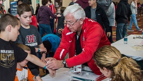 Terry Kahn helps a child with an armband while volunteering with Indiana Sports Corp.