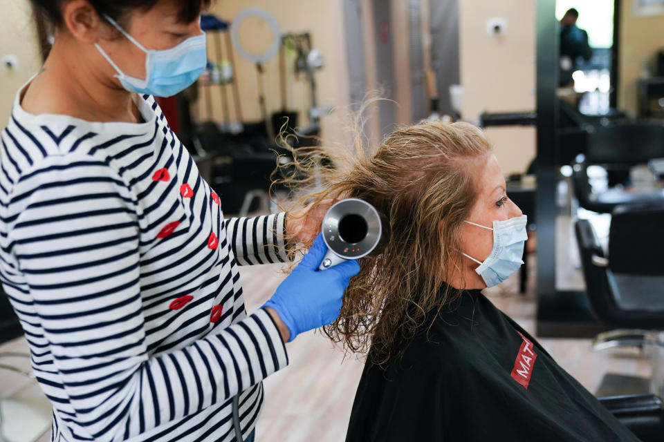 A stylist wearing a protective mask dries a customer's hair at a hair salon in Atlanta, Georgia, U.S., on Friday, March 24, 2020. Georgia's hair salons, tattoo parlors, bowling alleys, and other nonessential businesses were permitted to reopenÂ on Friday,Â after Governor Brian Kemp announced earlier this week that he'd ease the state's stay-at-home order. Photographer: Elijah Nouvelage/Bloomberg