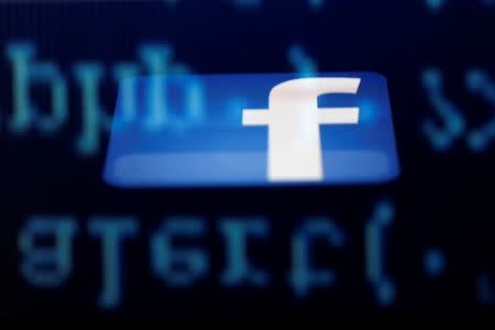 A Facebook logo on an Ipad is reflected among source code on the LCD screen of a computer, in this photo illustration taken in Sarajevo June 18, 2014. REUTERS/Dado Ruvic/Files