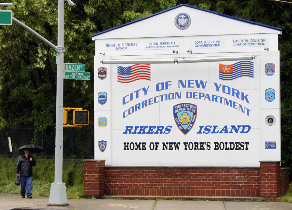 FILE - In this May 17, 2011, file photo, a man walks near the sign at the entrance to the Rikers Island jail in New York. Jerome Murdough, a 56-year-old mentally ill inmate at Rikers Island jail, "baked" to death in his overheated cell during one of the coldest recorded winters in city history. According to documents obtained by The Associated Press, jail officials were aware of malfunctioning heating equipment and requested repairs the last day Murdough was seen alive, but the needed work didn't happen until it was too late because of a long holiday weekend.(AP Photo/Seth Wenig, File)