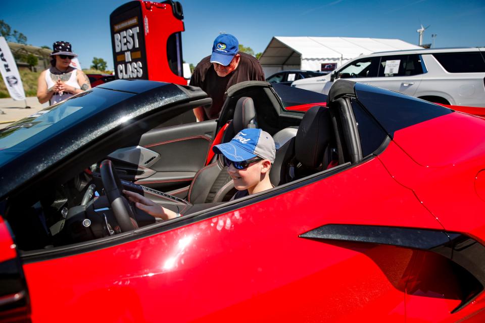 Riley Monson, 13, sits in a new Corvette with his father Bryce Monson at the All Iowa Auto Show in 2021.