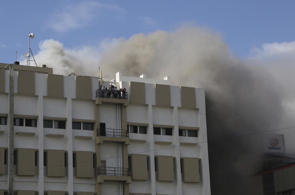People awaiting rescue stand on the balcony of a nine-story building with offices of a state-run telephone company during a fire in Mumbai, India, Monday, July 22, 2019. (AP Photo/Rafiq Maqbool)