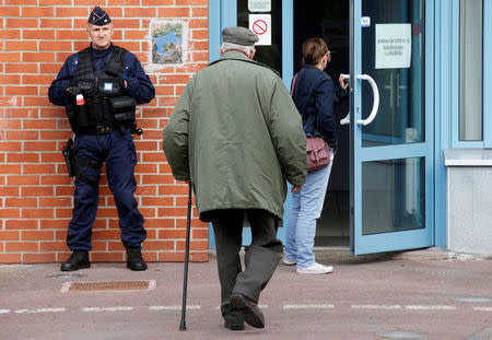 A policeman secures the entrance of a polling station as people arrive to vote in the first round of 2017 French presidential election in Henin-Beaumont, France, April 23, 2017. REUTERS/Pascal Rossignol