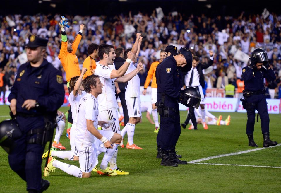 Real' Madrid players celebrate, as riot policemen put on their helmets, at the end of the final of the Copa del Rey between FC Barcelona and Real Madrid at the Mestalla stadium in Valencia, Spain, Wednesday, April 16, 2014. Real defeated Barcelona 2-1. (AP Photo/Manu Fernandez)