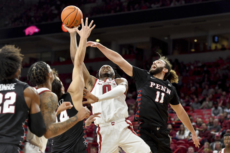 Arkansas guard Stanley Umude (0) shoots between Pennsylvania defenders Max Martz (14) and Michael Moshkovitz (11) during the first half of an NCAA college basketball game Sunday, Nov. 28, 2021, in Fayetteville, Ark. (AP Photo/Michael Woods)