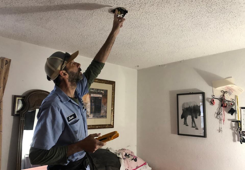 Jason Chedester checks the ceiling fan wiring, which emits sparks in the Hernandez home if someone flips on the light switch.