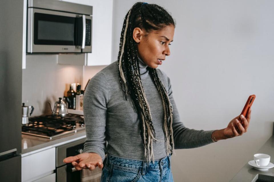 Frustrated Black woman looking at her cell phone