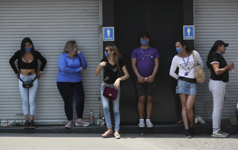 Sexual workers, wearing protective face masks, stand in line as they wait to receive a monetary incentive offered by the mayor to stay home in a measure to curb the spread of the new coronavirus, in Mexico City, Saturday, April 4, 2020. Mexico has started taking tougher measures against the new coronavirus, but some experts warn the country is acting too late and testing too little to prevent the type of crisis unfolding across the border in the United States. (AP Photo/Fernando Llano)