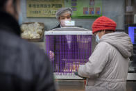 A clerk wears a face mask as he waits for a customer to pay at a bakery in Beijing, Saturday, Feb. 29, 2020. The coronavirus outbreak's impact on the world economy grew more alarming on Saturday, even as President Donald Trump denounced criticisms of his response to the threat as a "hoax" cooked up by his political enemies. (AP Photo/Mark Schiefelbein)