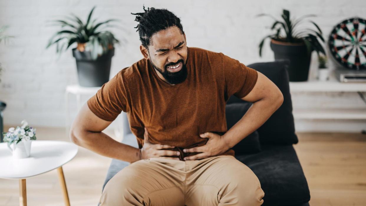 Hombre se toca el abdomen con dolor. 