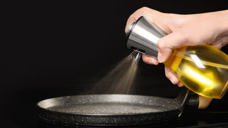 person spraying pan with oil