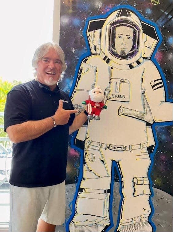 Steve Young holds the Surfing Santas of Cocoa Beach plush toy that he's taking to space inside Pineapples in downtown Eau Gallie.