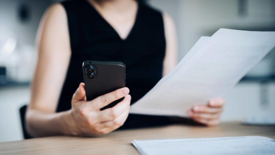 young Asian woman using online banking app on smartphones trying to figure out How long should you keep bank statements.