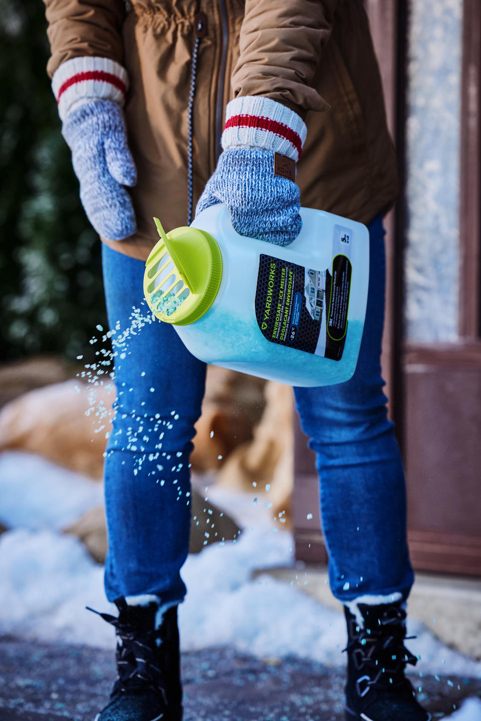 Woman sprinkling Yardworks Envirosafe ice melter from Canadian Tire on a walkway