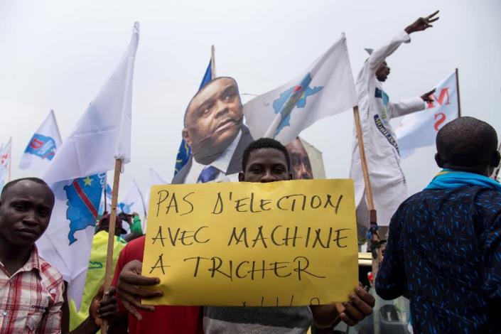 An opposition supporter holds a sign reading "No election with a cheating machine" -- there have been concerns about the use of electronic voting machines in DRC's poll (AFP Photo/Junior D. KANNAH)