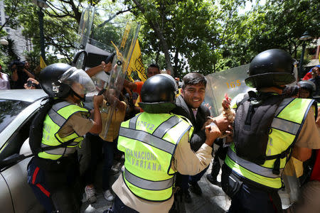 Conrado Perez (C), deputy of the Venezuelan coalition of opposition parties (MUD), carries a chicken while clashing with riot police during a protest outside the offices of the Venezuela's ombudsman in Caracas, Venezuela April 3, 2017. REUTERS/Carlos Garcia Rawlins