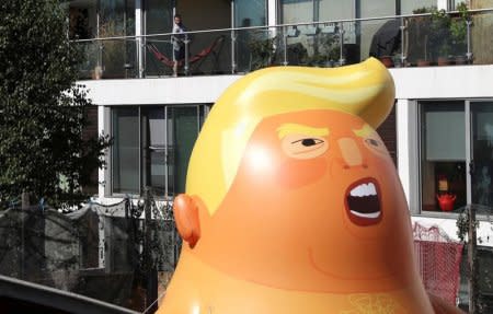 FILE PHOTO: A man looks from his balcony as people inflate a helium filled Donald Trump blimp which they hope to deploy during The President of the United States' upcoming visit, in London, Britain, June 26, 2018. REUTERS/Simon Dawson