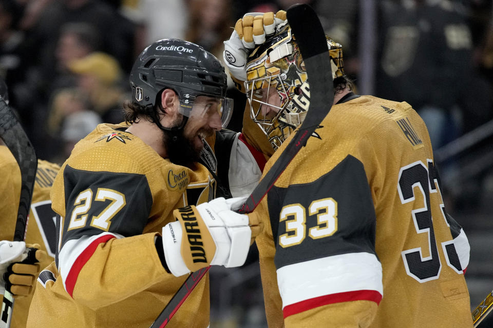Vegas Golden Knights defenseman Shea Theodore (27) celebrates with goaltender Adin Hill (33) after Game 1 of the NHL hockey Stanley Cup Finals against the Florida Panthers, Saturday, June 3, 2023, in Las Vegas. The Vegas Golden Knights defeated the Panthers 5-2. (AP Photo/John Locher)