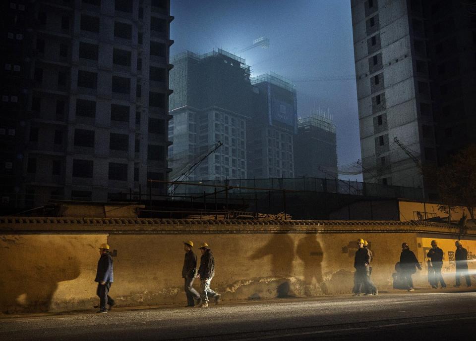 北京的工人們晚上下班後從在建的公寓樓前走過（資料圖）