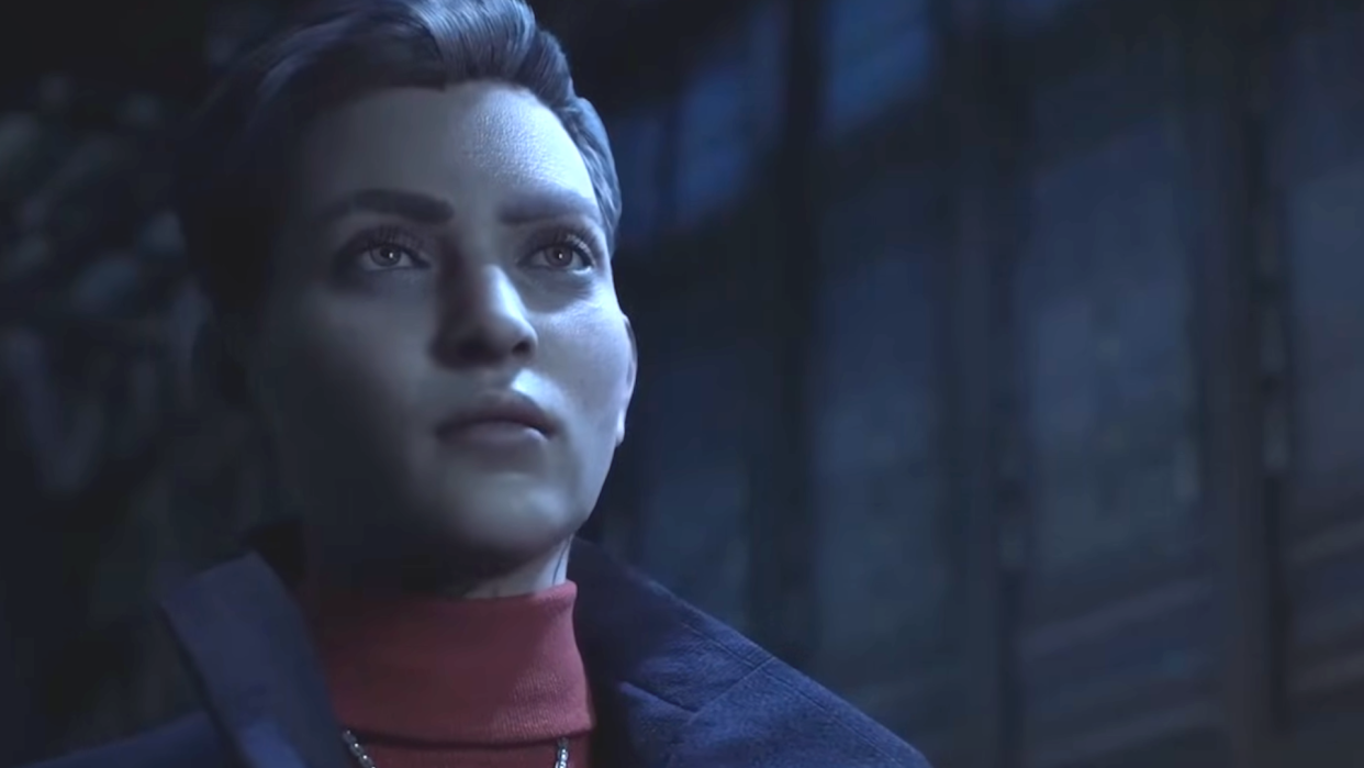  A screenshot of Phyre, the protagonist of Vampire: The Masquerade - Bloodlines 2, a severe-looking woman with short cropped hair and a collared coat, poised stoically in darkness. 