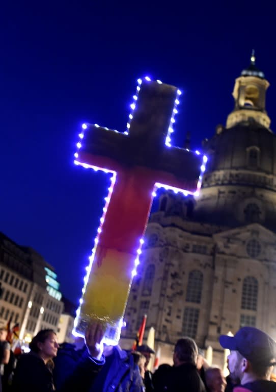 A PEGIDA supporter holds a cross during an ant-migrant rally in Dresden, eastern Germany, on October 5, 2015